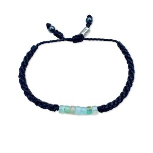 Handmade Rumi Sumaq Peruvian Opal rope bracelet in black cord with seven genuine Peruvian Opal stones, Hematite accents, and silver tone logo bead. Custom hand-knotted by Quechua designer Coco on Martha’s Vineyard, this adjustable bracelet fits men, women, and kids. Perfect personalized October birthstone or 24th anniversary gift jewelry.