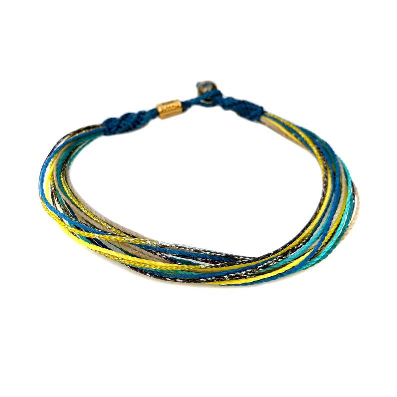 Unisex handmade macramé anklet in blue yellow aqua and purple, customized for the perfect fit. A fixed-size ankle bracelet featuring a durable waxed nylon cord and a Hematite stone bead. Ideal for surfers, beachgoers, and adventurers, this waterproof and washable anklet can be worn daily. The perfect gift for men and women who love handmade artisan jewelry, coastal living, and minimalist beach accessories.