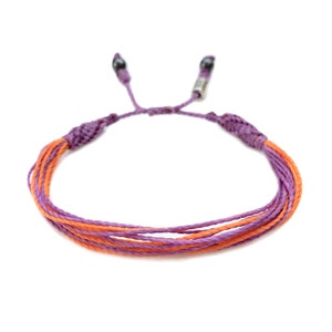 May include: A purple and orange braided bracelet with silver beads at the ends.