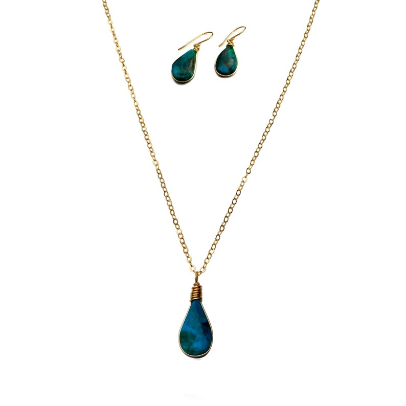 Rumi Sumaq gemstone jewelry is handmade on Marthas Vineyard. Gold fill Chrysocolla pendant necklace and earrings set, wire-wrapped by hand in the Rumi Sumaq art studio. The teardrop gemstone necklace comes on a delicate chain while the coordinating dangle earrings add effortless elegance. Chrysocolla’s calming energy makes this artisan jewelry set ideal for those seeking emotional balance and self-expression. A perfect birthday, anniversary gift packaged in a Rumi Sumaq box.