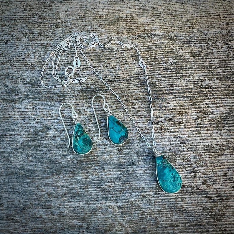 Chrysocolla jewelry gift set handcrafted by Coco Paniora Salinas in the Rumi Sumaq studio, featuring a wire-wrapped teardrop pendant necklace and matching dangle earrings in sterling silver or gold fill. This artisan gemstone jewelry celebrates the natural beauty of Chrysocolla, a stone known for promoting communication and emotional harmony. Ideal for birthdays, anniversaries, or holiday gifting, this set arrives beautifully packaged.