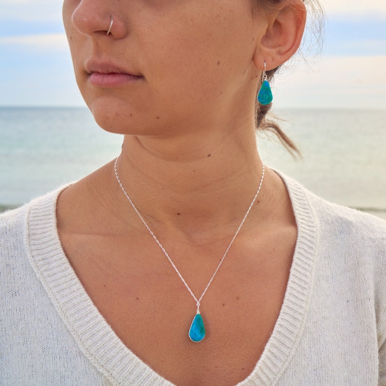Unique Chrysocolla jewelry set including a sterling silver or gold fill teardrop pendant necklace and matching dangle earrings wire-wrapped by hand in the Rumi Sumaq studio. This turquoise set is perfect for nature lovers and those who appreciate healing crystal jewelry. Peruvian Chrysocolla’s soothing energy supports emotional balance and self-confidence making it a thoughtful gift for any occasion. Arrives in a Rumi Sumaq gift box, ready for birthdays, anniversaries, or holiday gifting.
