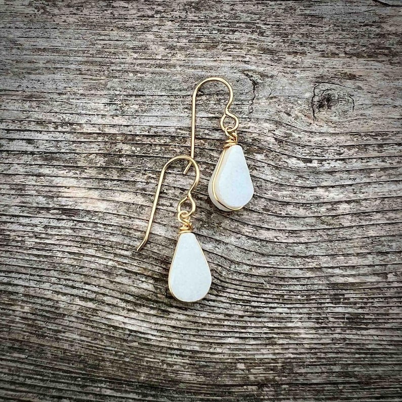 Elegant teardrop earrings handcrafted with genuine white jasper gemstones, these dangle earrings are designed for those who love boho jewelry sets with spiritual meaning. The lightweight stones are suspended from gold fill or sterling silver French ear wires making them a unique gift for her. Designed by Quechua artist Coco Paniora Salinas these earrings embody craftsmanship and energy healing. The white teardrop stone earrings come packaged ready for gifting in a beautiful RumiSumaq gift box.