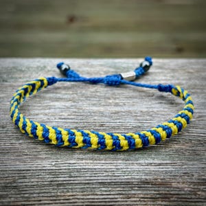 May include: A blue and yellow braided bracelet with black beads at the ends.