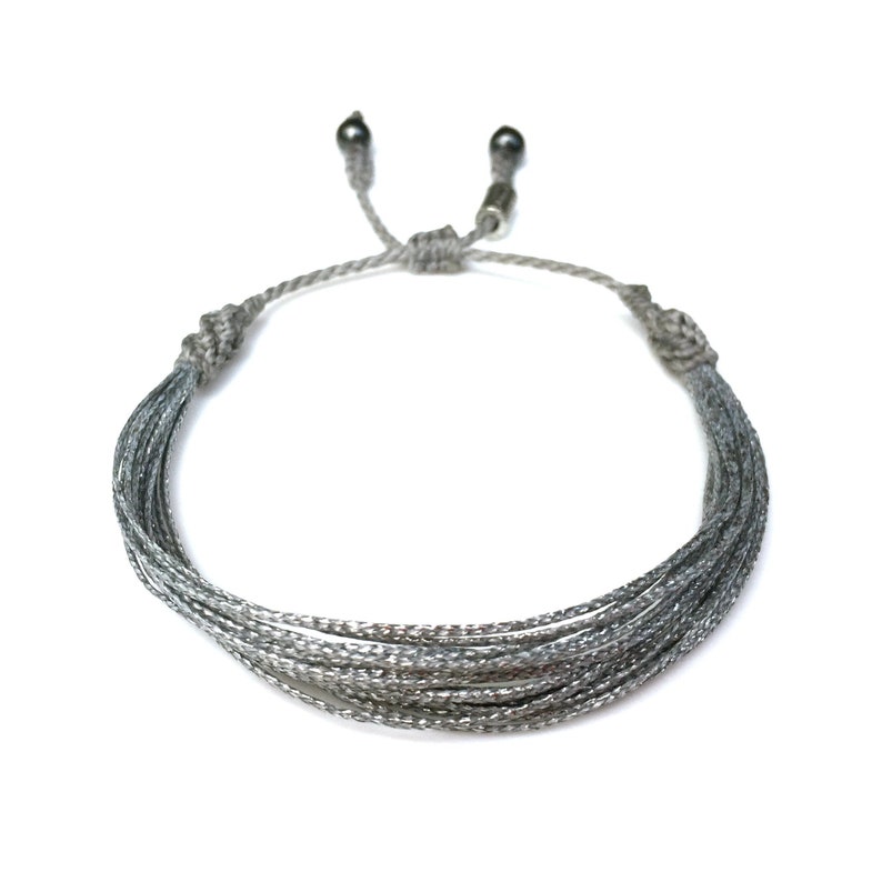 Silver string awareness bracelet, handmade for Parkinson’s awareness, schizophrenia awareness, and dyslexia awareness. This silver awareness bracelet is fully adjustable, making it a perfect fit for men, women, and kids. A meaningful silver ribbon awareness bracelet to support causes like sciatic pain, disabled children, and neurological disorders. Lightweight, comfortable, and stylish. Rumi Sumaq handmade jewelry, silver awareness jewelry, awareness wristband. Silver String Awareness Bracelet