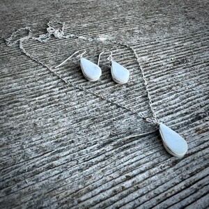 This handmade white jasper necklace and earrings set is a stunning piece of healing crystal jewelry crafted by Quechua designer Coco Paniora Salinas in his Rumi Sumaq art jewelry studio on Marthas Vineyard. The teardrop white jasper pendant necklace and matching earrings are available in silver or 14k gold fill making them an elegant choice for everyday wear or spiritual healing. Known for its calming energy white jasper enhances balance and clarity making this an ideal energy healing gift.