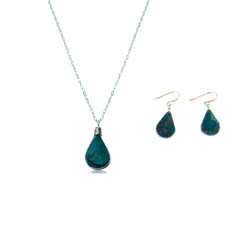 Sterling silver Chrysocolla jewelry set featuring a teardrop pendant necklace and dangle earrings handcrafted by Coco Paniora Salinas. The vibrant blue-green Chrysocolla stones are wire-wrapped in silver highlighting their natural beauty. This gemstone is said to promote inner peace and harmony. Designed for lovers of boho chic jewelry this set comes ready for gifting in an elegant Rumi Sumaq gift box. Chrysocolla silver necklace set with turquoise blue dangle earrings and pendant necklace.