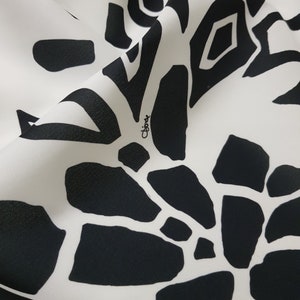 Puede incluir: Patr&oacute;n abstracto en blanco y negro sobre una tela blanca con la palabra "Chlo&eacute;" escrita en cursiva.
