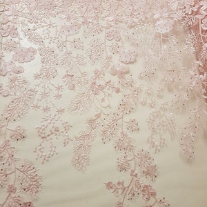 May include: Pink floral lace fabric with a delicate pattern and small beads. The lace has a sheer, lightweight feel and is perfect for adding a touch of elegance to any project.