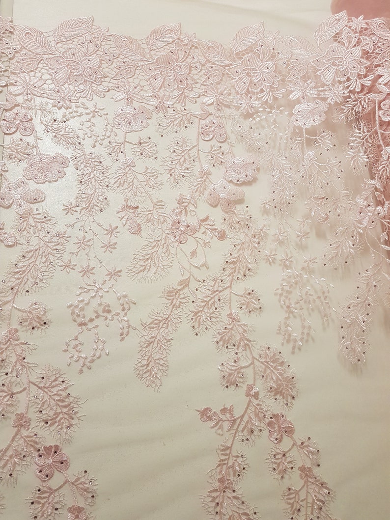 May include: Pink floral lace fabric with a delicate pattern and small beads. The lace has a sheer, lightweight feel and is perfect for adding a touch of elegance to any project.