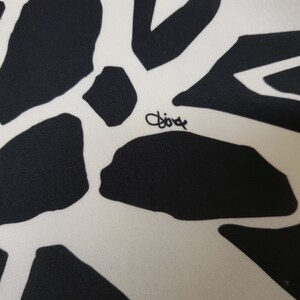 Puede incluir: Primer plano de una tela blanca con un patr&oacute;n abstracto en blanco y negro. La tela tiene la palabra "Dior" escrita en tinta negra.