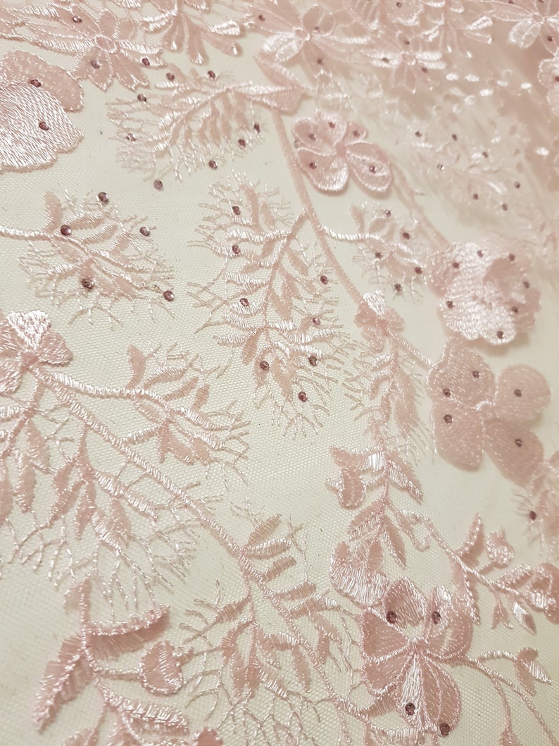 May include: Pink floral lace fabric with delicate embroidery and small, shiny beads.