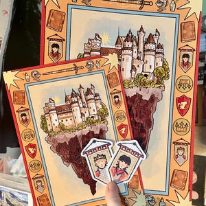 May include: Two rectangular art prints and two small stickers featuring a fantasy castle on a floating island. The border includes illustrations of swords, helmets, books, and shields with portraits of two characters in a medieval style.