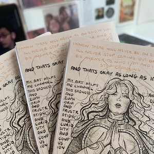 May include: Several beige art prints with a detailed black and white illustration of a person in armour with hands clasped. The prints feature handwritten text including "And That's Okay" and other phrases.