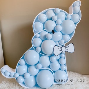 K&ouml;nnte beinhalten: Ein hellblaues Ballontier in Form eines Elefanten mit einer schwarzen Schleife. Der Elefant besteht aus vielen kleinen Ballons und steht auf einer wei&szlig;en Oberfl&auml;che. Der Text "paper & luxe decor" ist unten im Bild zu sehen.