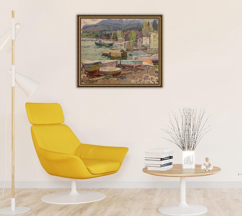 May include: A framed painting depicting a lakeside scene with boats docked along the shore. The painting features a variety of colors, including blues, greens, and browns. The boats are a mix of wooden and metal, and some have colorful sails.
