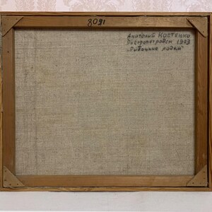 May include: The back of a framed painting on canvas. The canvas is a light beige color and the frame is a light brown wood. The painting is signed "Anatoliy Kostenko Dnepropetrovsk 1993 "Rybachie lodki" ".