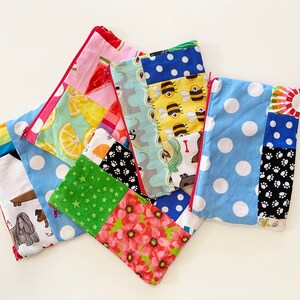 以下が含まれることがあります： レモン、蜂、足跡、星などのさまざまなパターンが施された、カラフルなジッパー付きポーチ6個セット。ポーチは布製で、赤いジッパーが付いています。