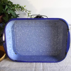 May include: A blue enamel baking dish with a white speckled interior. The dish is rectangular and has a slightly rounded rim.