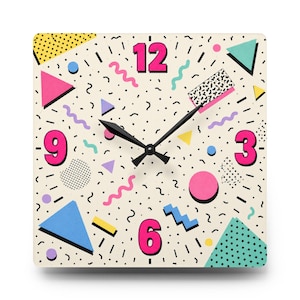 May include: A square wall clock with a cream-colored face featuring a pattern of pink, blue, and yellow geometric shapes, including triangles, circles, and squiggly lines. The numbers 3, 6, 9, and 12 are in bold pink, with black clock hands.