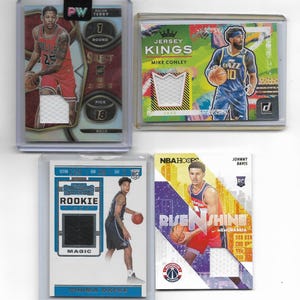 May include: Four basketball trading cards in protective cases. The cards feature images of NBA players in their team uniforms, with jersey swatches. The cards include the names Dalen Terry, Mike Conley, Chuma Okeke, and Johnny Davis.