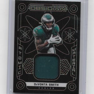 May include: A white ceramic mug with a black handle and the text "But First, Coffee" in a bold, black font. The mug is set against a blurred background, suggesting a cozy setting.