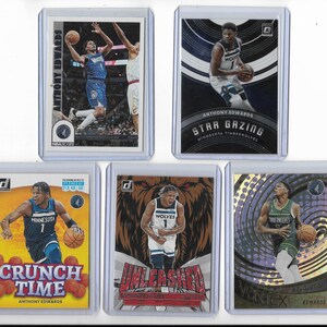 Op de afbeelding: Vijf basketbal trading cards met Anthony Edwards van de Minnesota Timberwolves. De kaarten tonen actiebeelden en diverse ontwerpen, waaronder de thema's "Crunch Time" en "Star Gazing". Elke kaart zit in een beschermhoes.