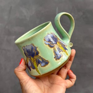 May include: A set of three ceramic mugs with a speckled, matte finish in cream, light grey, and dark grey. Each mug has a simple, minimalist design, ideal for coffee or tea.