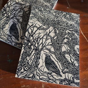 May include: Two black birds are perched on branches of a tree with intricate black and white line art. The background is a cream colour.