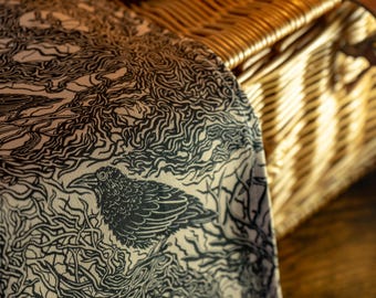 May include: A woven textile featuring a high-contrast black and white pattern of detailed ravens perched among intricate, swirling tree branches and tangled roots. The fabric displays a dense, graphic illustration style with fine line work.