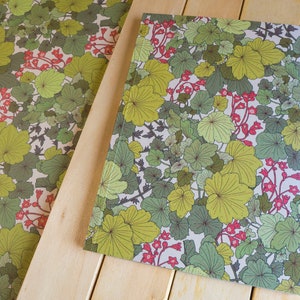 May include: A sheet of wrapping paper with a green and red floral pattern. The pattern features stylized leaves and flowers on a white background.