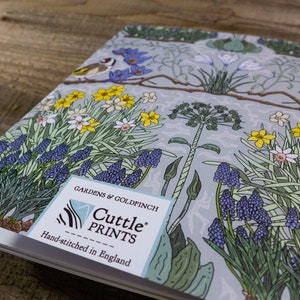 May include: A blue and green floral notebook with a goldfinch and the text "Gardens & Goldfinch Cuttle Prints Hand-stitched in England" on the front cover.