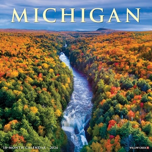 May include: A 2026 18-month calendar featuring a scenic view of Michigan's natural beauty. The image showcases a river winding through a forest with vibrant autumn foliage in shades of orange, yellow, and green. The word "MICHIGAN" is at the top.