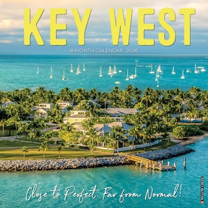 May include: A Key West 18-month calendar for 2026. The cover features a scenic view of Key West with turquoise water, sailboats, palm trees, and houses. The text "KEY WEST" is in large yellow letters, with the phrase "Close to Perfect. Far from Normal!"
