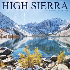 May include: A calendar titled "HIGH SIERRA" with a scenic landscape of a lake reflecting snow-capped mountains under a bright sky. The calendar is for 18 months and the year 2026. The image features a serene lake with rocks and yellow bushes in the foreground.