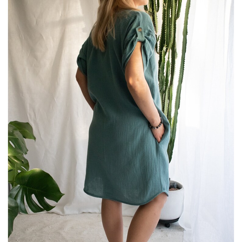 Pu&ograve; includere: Un abito casual blu-verde, a maniche corte, con un dettaglio a bottone sulla manica. L'abito ha una vestibilit&agrave; rilassata e un orlo leggermente curvo.