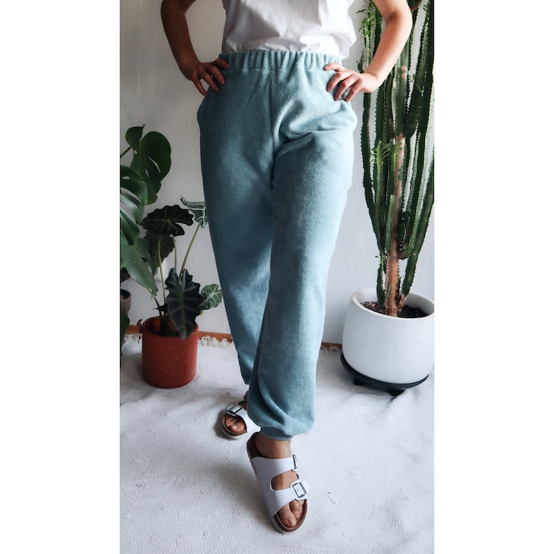May include: A person wearing a pair of light blue sweatpants with a white top and white sandals.