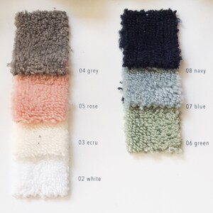 May include: Swatch card showing 10 different colors of fabric. The colors are: white, ecru, rose, grey, green, blue, navy. The fabric is a soft, fluffy, terry cloth.