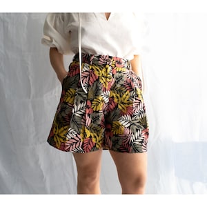 May include: Black, pink, yellow, and green floral print shorts with a high waist and pleats.