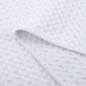 Puede incluir: Toalla de cocina blanca de tejido de gofre. La toalla est&aacute; doblada por la mitad y la textura del tejido es visible.
