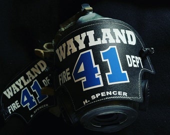 May include: Black firefighter helmet with the text "WAYLAND FIRE DEPT 41" in white and blue. The name "H. Spencer" is printed below the numbers. A matching black helmet shield is also visible.