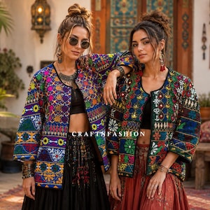 May include: Two open-front jackets featuring intricate, multi-coloured embroidery with floral and geometric patterns in shades of blue, green, yellow, and red. The jackets have three-quarter length sleeves and are worn over black crop tops.