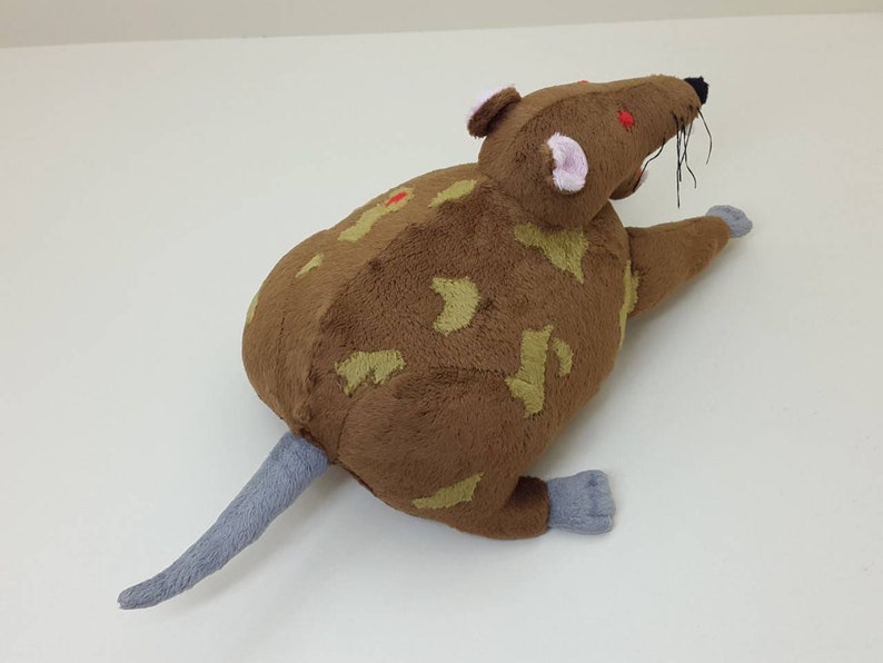 K&ouml;nnte beinhalten: Ein braunes und hellbraunes Pl&uuml;schrat mit roten Augen und einem grauen Schwanz. Die Ratte liegt auf der Seite mit dem Kopf zur Seite gedreht.