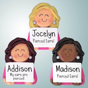 May include: Three personalized ornaments featuring cartoon girls with different hair colors and skin tones. Each ornament has a sign with a name and a message about pierced ears. The names are Jocelyn, Addison, and Madison.