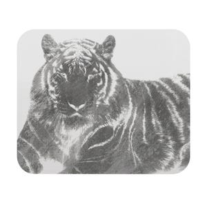 Könnte beinhalten: Ein rechteckiges Mauspad mit einer einfarbigen, anthrazitfarbenen Illustration eines Tigers. Der Tiger ist in einer frontalen Pose dargestellt, mit detaillierten schwarzen und grauen Streifen, strukturiertem Fell und einem fokussierten Gesichtsausdruck.