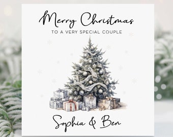 May include: A white Christmas card with a watercolor illustration of a silver Christmas tree with presents underneath. The text "Merry Christmas to a very special couple" is at the top of the card and the names "Sophia & Ben" are at the bottom.