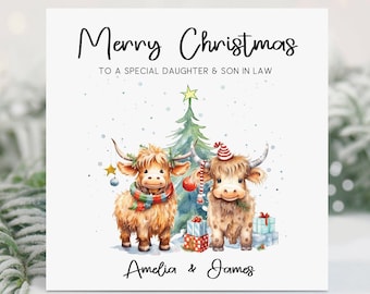 May include: A Christmas card with the text "Merry Christmas to a special daughter & son in law". The card features two Highland cows, a Christmas tree, and gifts. The names "Amelia & James" are written at the bottom.