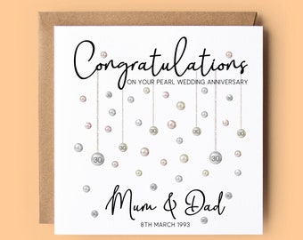 May include: A white card with a black and white design of pearls and the text "Congratulations on your Pearl Wedding Anniversary" and "Mum & Dad 8th March 1993".