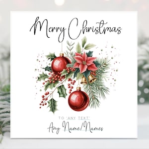 May include: A square Christmas card with the words "Merry Christmas" in elegant script. The card features a watercolor illustration of red ornaments, holly, berries, a poinsettia, and gold bells. The text "TO 'ANY TEXT' Any Name/Names" is also included.