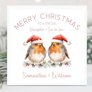May include: A Christmas card with the text "MERRY CHRISTMAS TO A SPECIAL Daughter & Son in Law". Two robins wearing Santa hats are perched on a holly branch. The names "Samantha & William" are printed below.